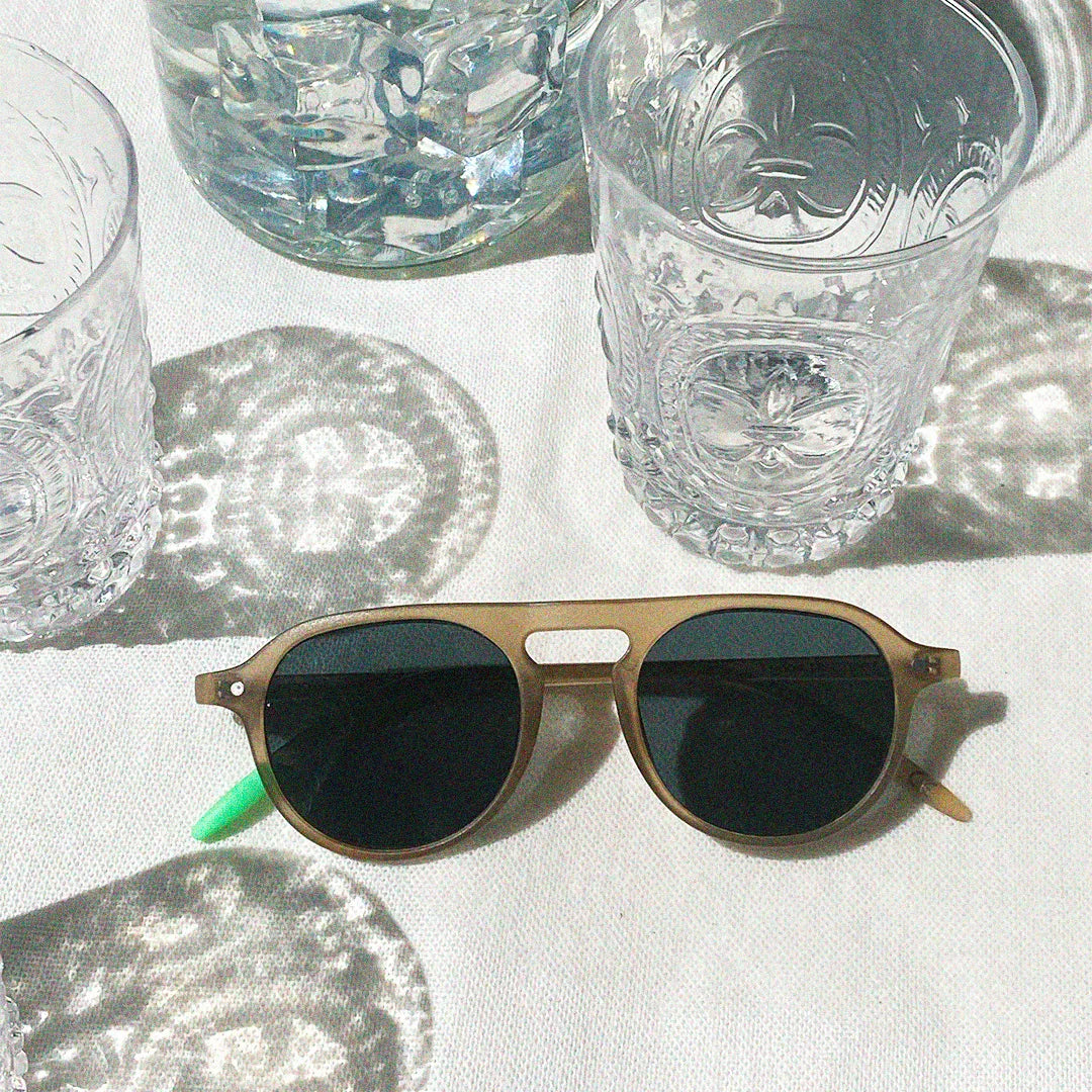 Photograph of a frame surrounded by clear drinking glasses.